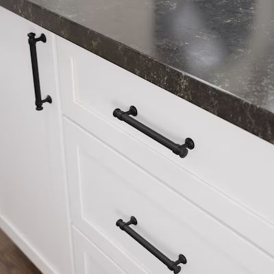 an image of a kitchen counter top with black pulls on it's drawers and handles