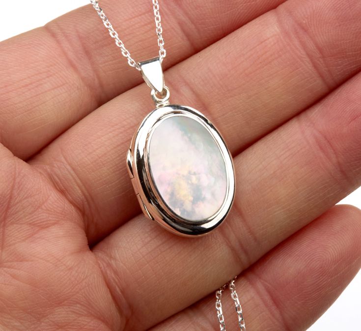 An oval sterling silver photo locket necklace with an oval bezeled mother of pearl on the front: 1. One shining, highly polished solid sterling silver locket (23 x 18* mm, 8 mm thick, 5.24 grams) * Dimensions measured without the bale. Its front has a piece of mother of pearl (19 x 13.5 mm) set in a raised bezel. Its back is plain and can be engraved with initials or a few words. 2. It has two photo slots insides. Photo insertion service available (selected/paid through the pulldown menu). If yo Cheap Sterling Silver Locket Necklace Gift, Mother Of Pearl Necklace Locket, Oval Locket Necklace Silver, Luxury Silver Engraved Locket Necklace, Silver Locket Necklace, Engraved Locket, Round Locket, Sterling Silver Locket, Oval Locket