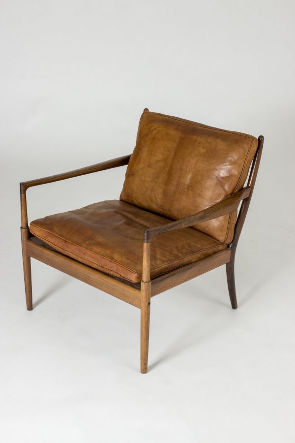 a brown leather chair sitting on top of a white floor next to a wooden frame