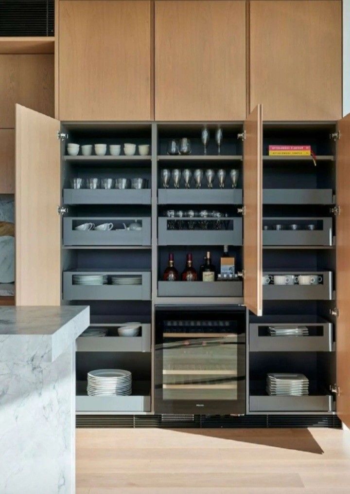 an open cabinet in the middle of a kitchen with plates and bowls on it's shelves