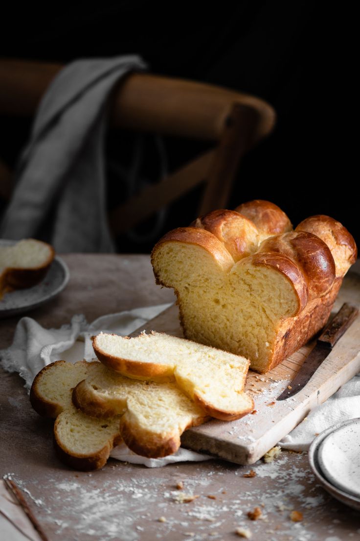 a loaf of bread sitting on top of a cutting board next to slices of bread