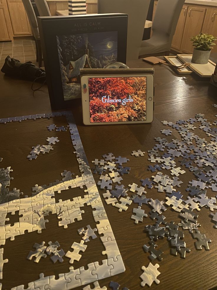 a table topped with puzzle pieces and a cell phone