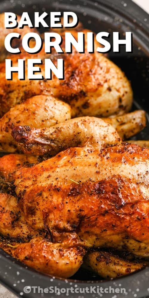 baked cornish hen in a cast iron skillet with text overlay that reads baked cornish hen