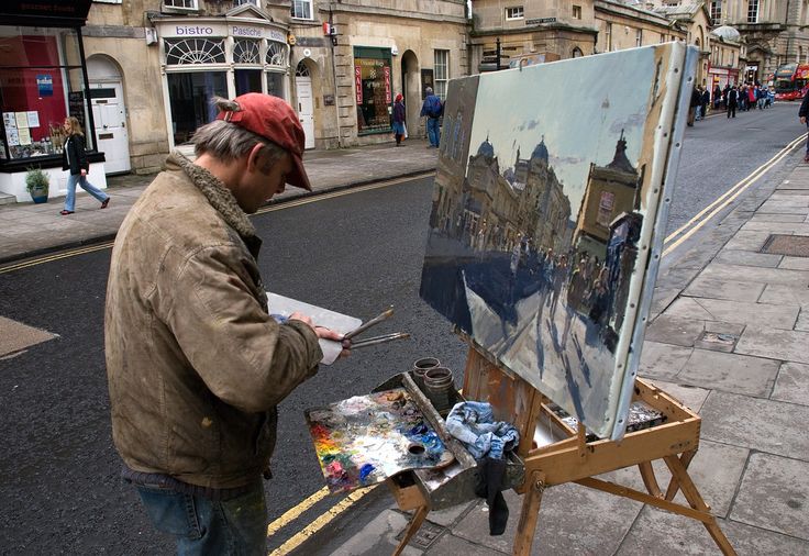 a man is painting on an easel in the street