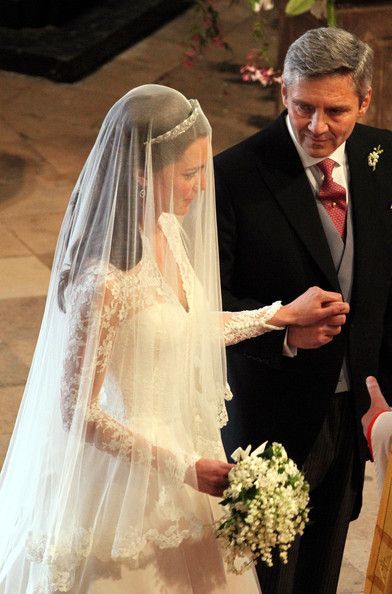 a man and woman standing next to each other in front of a wedding cake with flowers on it