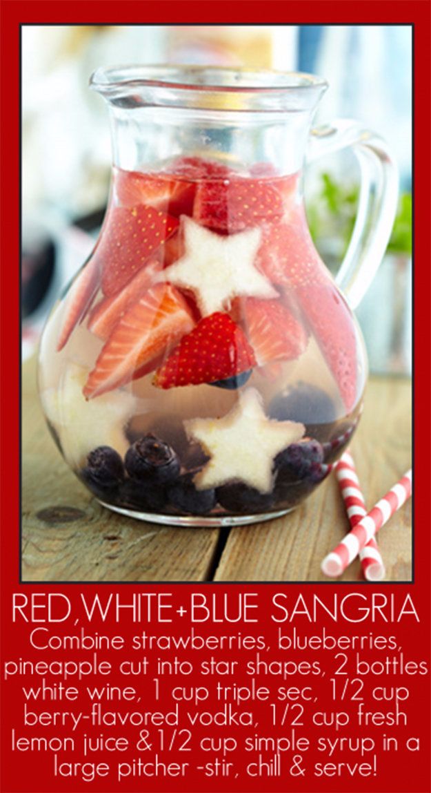 red white and blue sangria in a glass pitcher with strawberries, blueberries, and berries