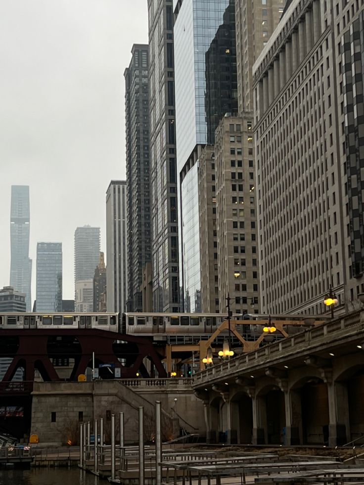 a train traveling over a bridge in the middle of a large city with tall buildings