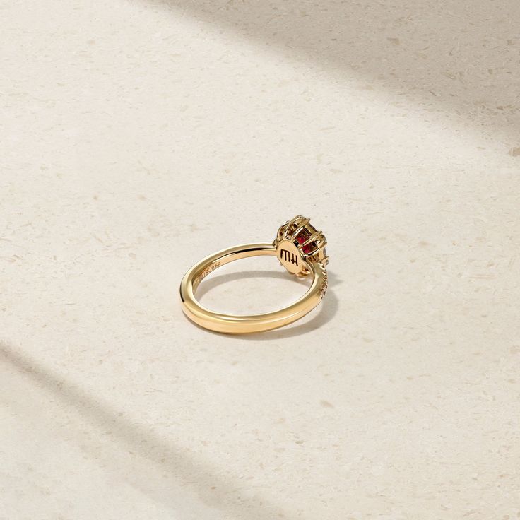 A glowing red ruby lays at the center of this meticulously crafted ring that's framed by a halo of twinkling round and baguette diamonds. Additional petite round diamonds sparkle along each end of the comfort fit shank to complete the look. Make this elegant and timeless adornment apart of your everyday jewelry rotation. Metal: 18kt Gold Ruby Weight: 0.60 ct. Round Diamond Weight: 0.25 ct. Baguette Diamond Weight: 0.22 ct. Measurements: 10.0 mm length *Please note that the listed ct. weights are Red Diamond Ring With Baguette Cut, Timeless Ruby Ring With Diamond Center Stone, Luxury Yellow Gold Ruby Ring With Halo, Elegant Ruby Ring With Diamond Halo, Elegant Ruby Ring With Halo, Elegant Ruby Halo Ring With Diamonds, Baguette Cut Ruby Ring With Diamond Center Stone, Baguette Cut Ruby Ring With Diamond, Classic Ruby Birthstone Ring With Halo Setting