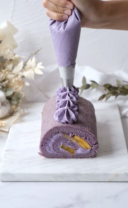 a person is using a knife to cut into a piece of cake with purple icing