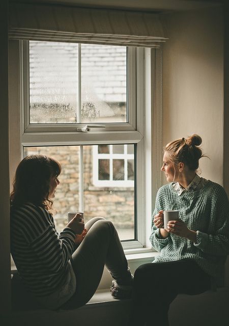 two women sitting next to each other in front of a window with the words geluk is je rijk voien net de menen on je je heen