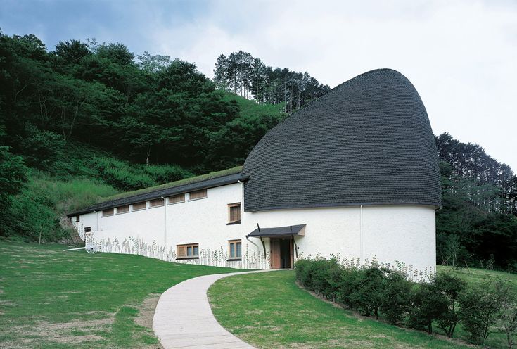 a white building with a black roof and a path leading to it