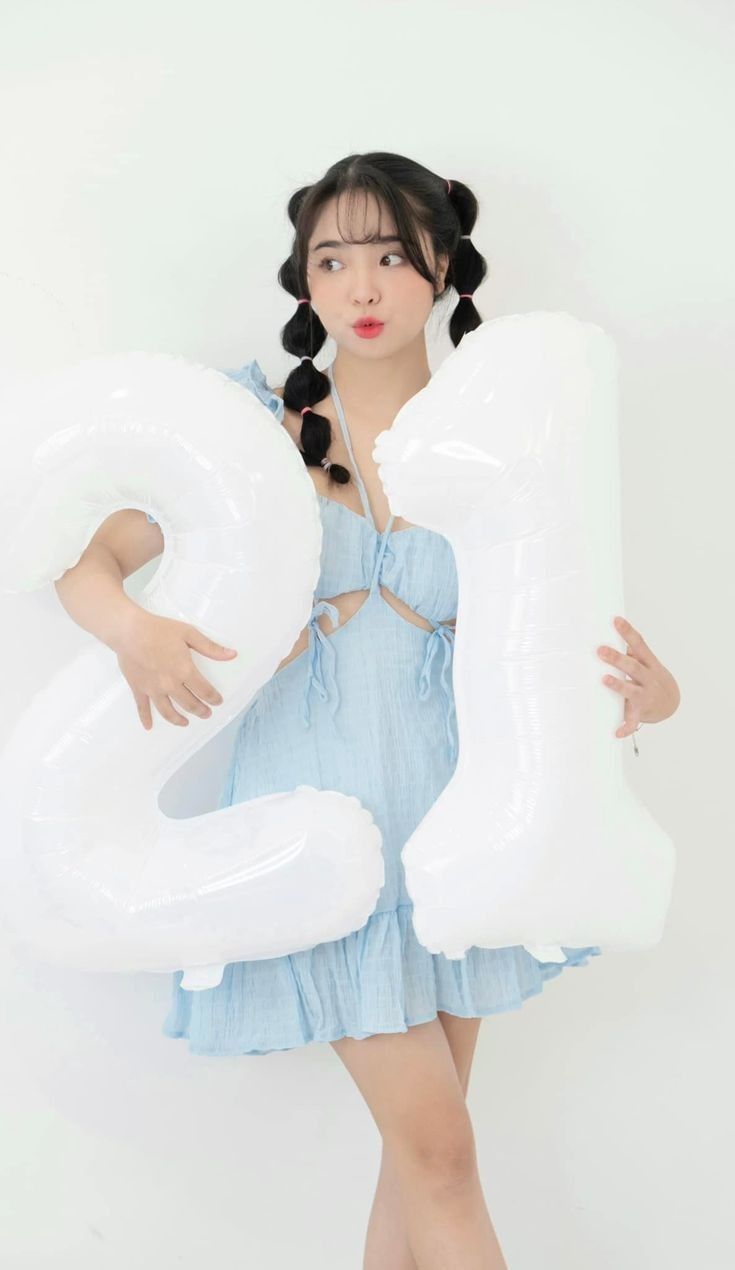 a woman holding an inflatable number twenty five balloon while posing for the camera