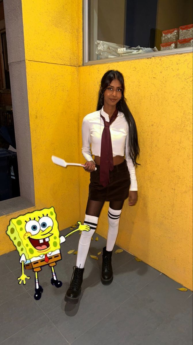 a woman dressed in costume standing next to a yellow wall with a fake spongebob on it