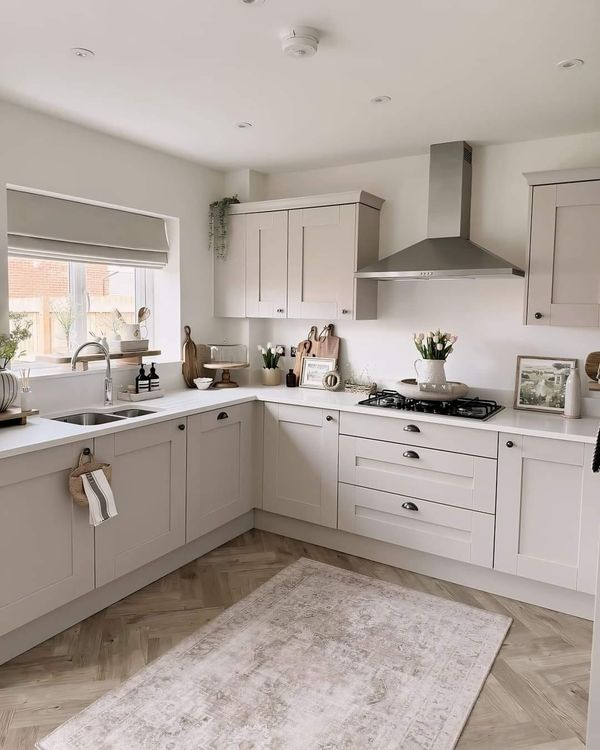 a large kitchen with white cabinets and beige rugs on the hardwood floored floor