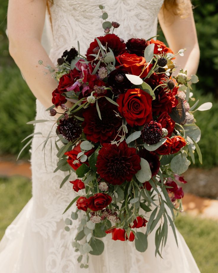 a bride holding a bouquet of red flowers