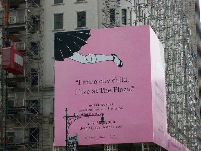 a large pink billboard on the side of a building with scaffolding around it