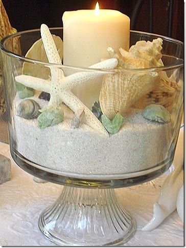 a glass bowl filled with sand and sea shells