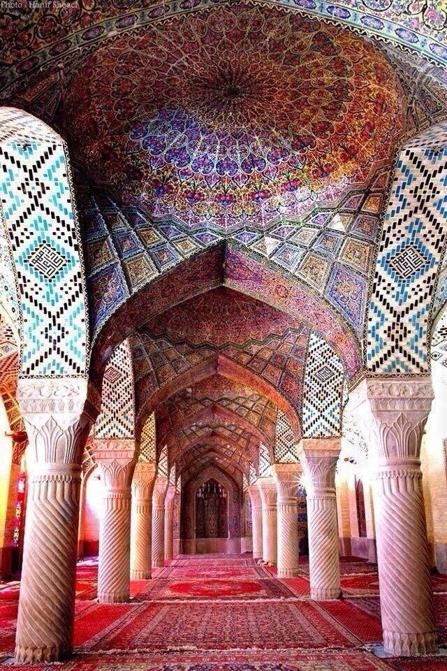 the inside of an ornate building with many pillars and arches, all decorated in colorful patterns