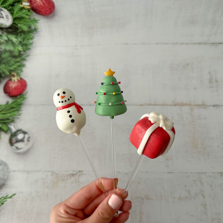 a hand is holding three christmas cake pops