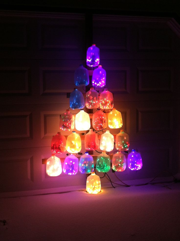 a christmas tree made out of many different colored lights in front of a garage door