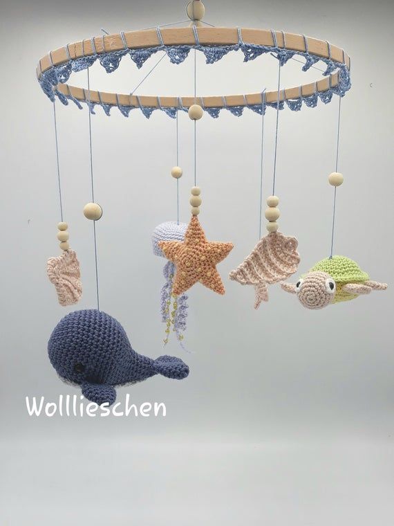 a crocheted sea animal mobile hanging from a wooden rod