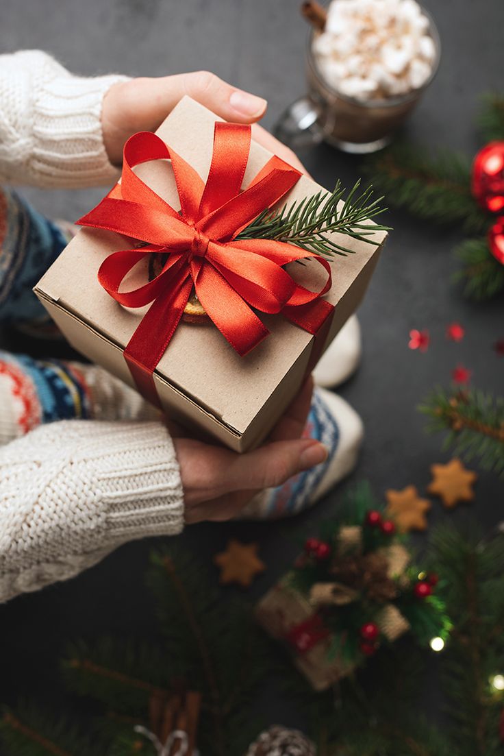 a person holding a wrapped present in front of christmas decorations