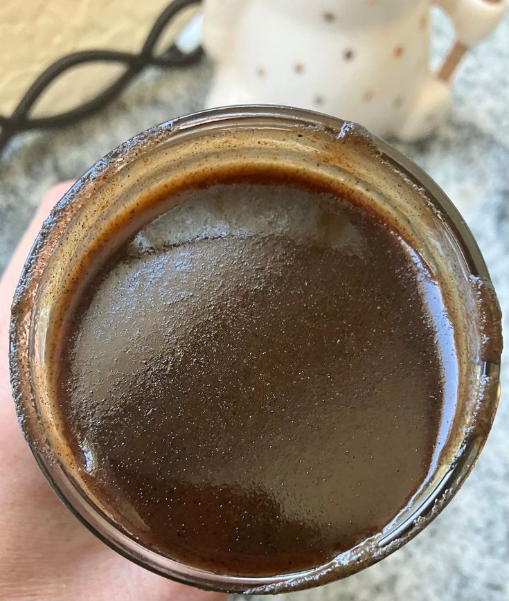 a hand holding a cup filled with brown liquid