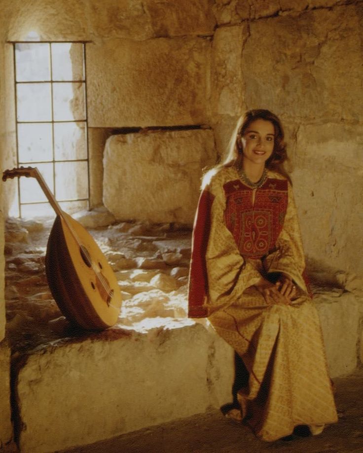 a woman sitting on a stone bench next to a window with a guitar in front of her