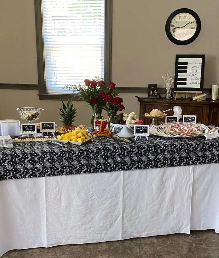 a table topped with lots of food on top of a white table cloth next to a window