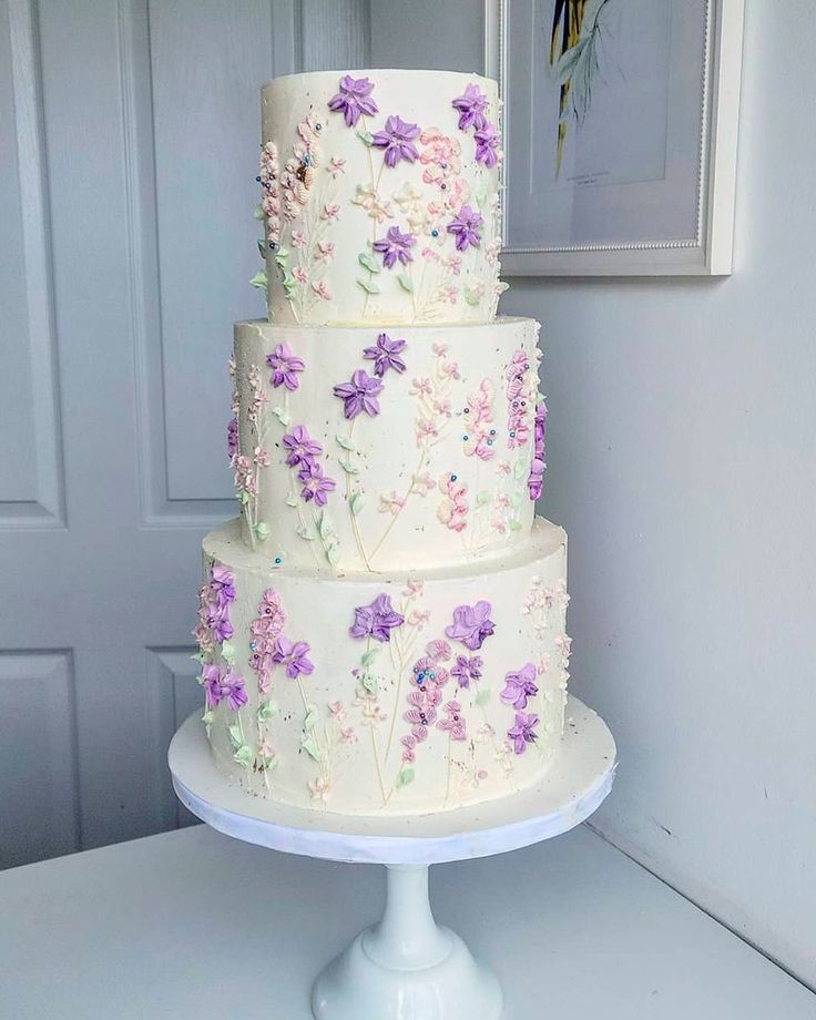 a three tiered cake with purple flowers on it