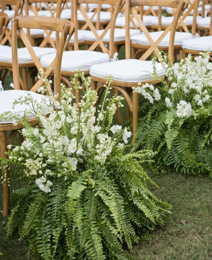 rows of chairs lined up with white flowers and greenery