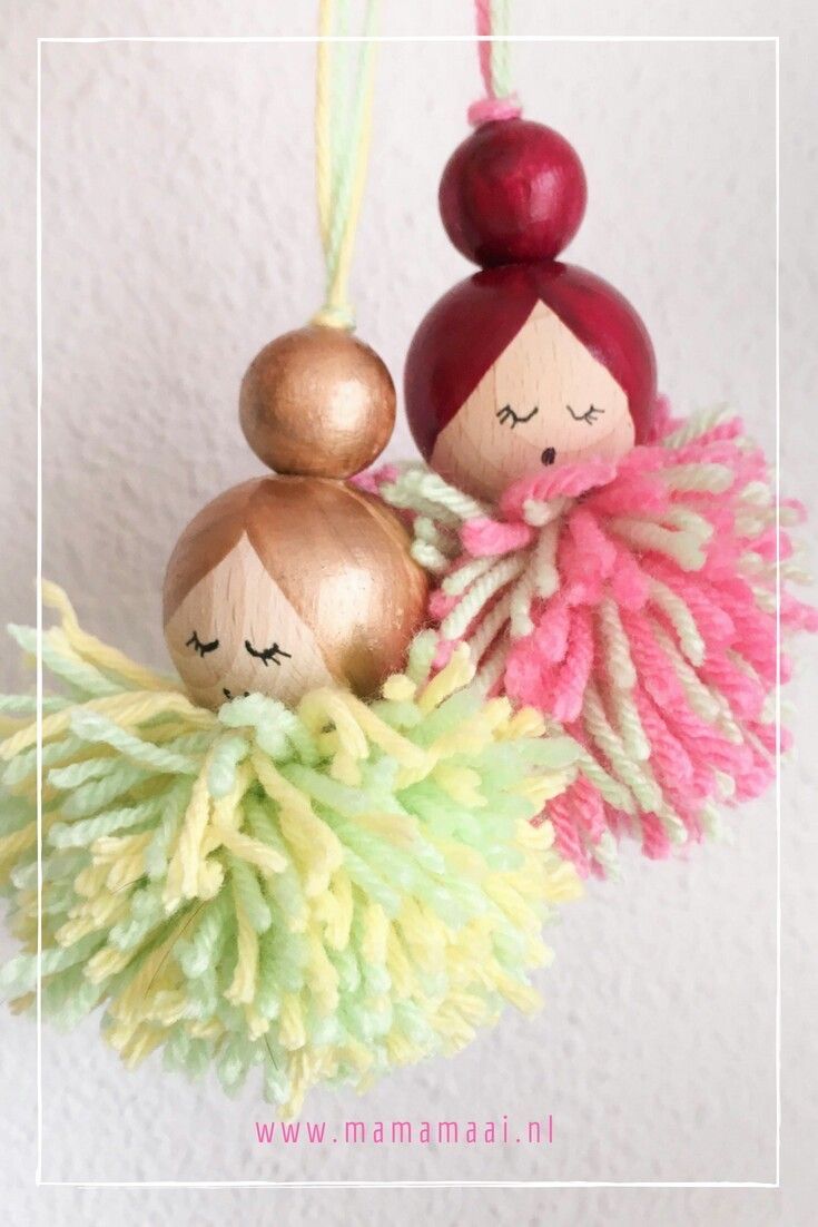 an ornament with two dolls hanging from it's sides on a wall