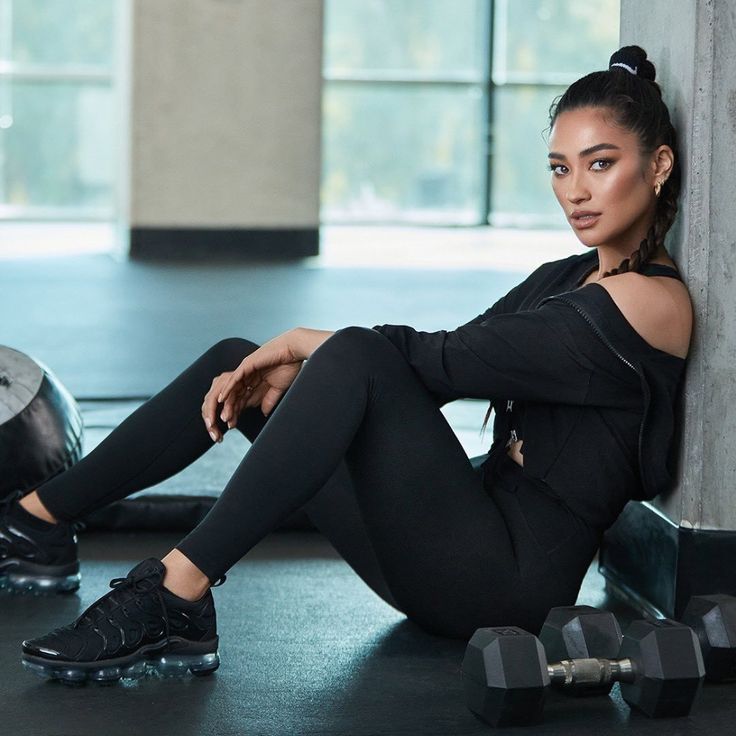 a woman is sitting on the floor with her legs crossed and looking at the camera