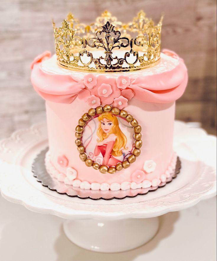 a pink princess cake with a gold crown on top is sitting on a white plate