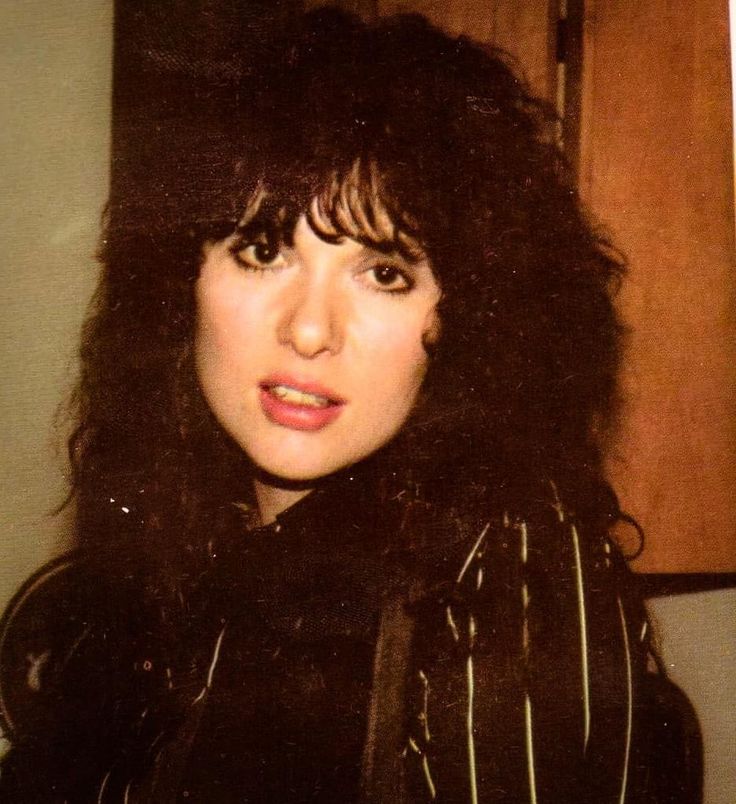 an old photo of a woman with dark hair and bangs, wearing a black jacket