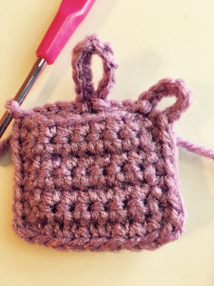 a crocheted purse sitting on top of a table next to a knitting needle