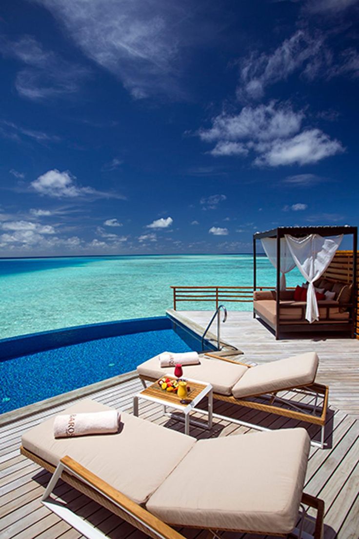 two lounge chairs sitting on top of a wooden deck next to an open swimming pool