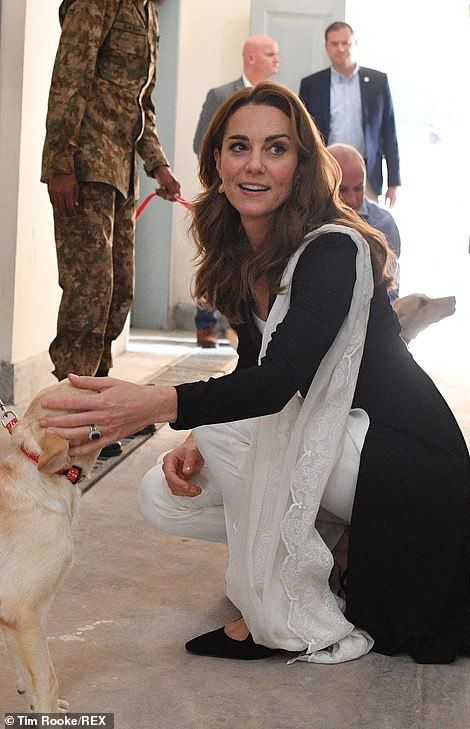 a woman kneeling down petting a dog while other people stand in line behind her