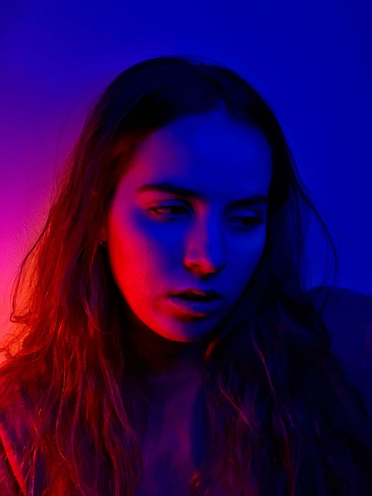 a woman with long hair standing in front of a purple and blue background