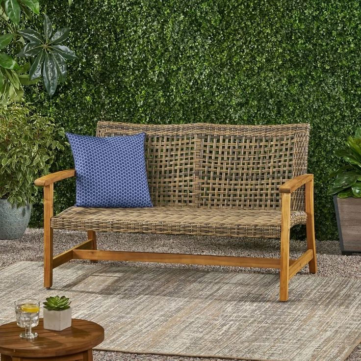 a wooden bench sitting on top of a rug in front of a green wall and potted plants