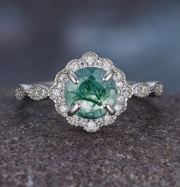 an oval cut green and white diamond ring on top of a granite surface with diamonds surrounding it