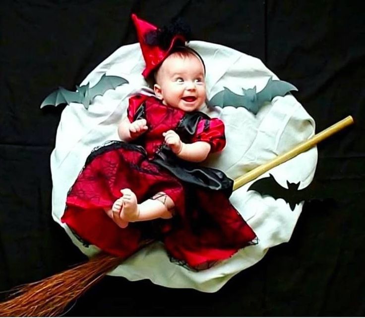 a baby dressed up as a witch with a broom