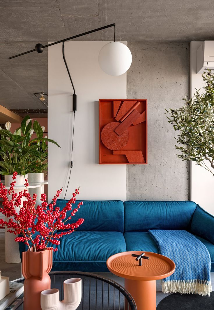 a living room with blue couches and red flowers in vases on the coffee table