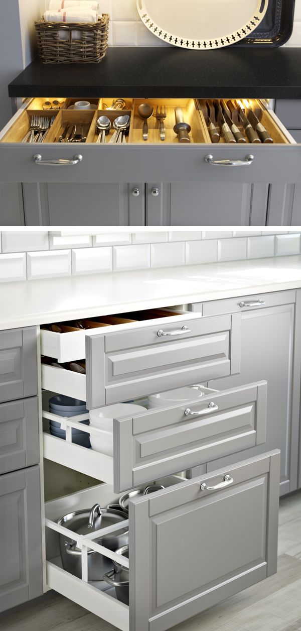 an open drawer in a kitchen with silver cabinets