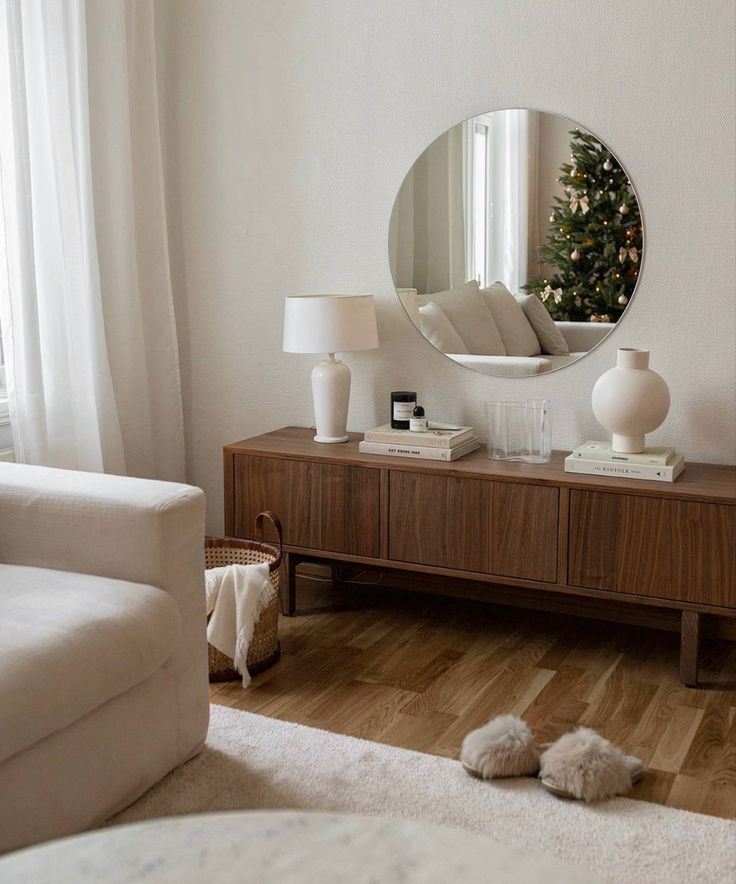 a living room with white furniture and a round mirror