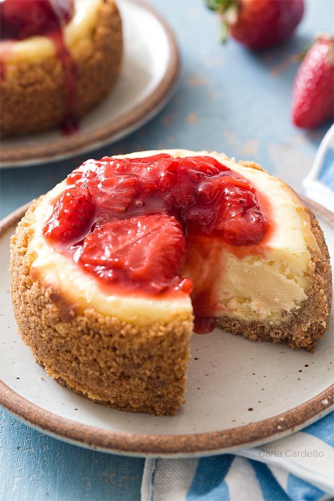 a cheesecake with strawberries on top is sitting on a plate and has one slice taken out