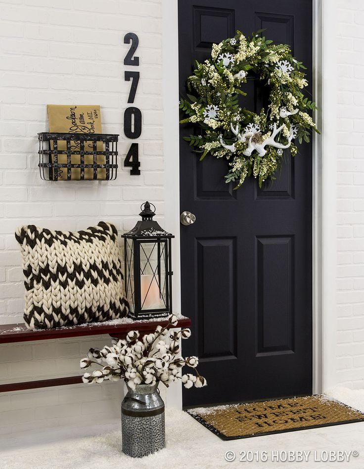 the front door is decorated for christmas with wreaths and decorations on display next to it