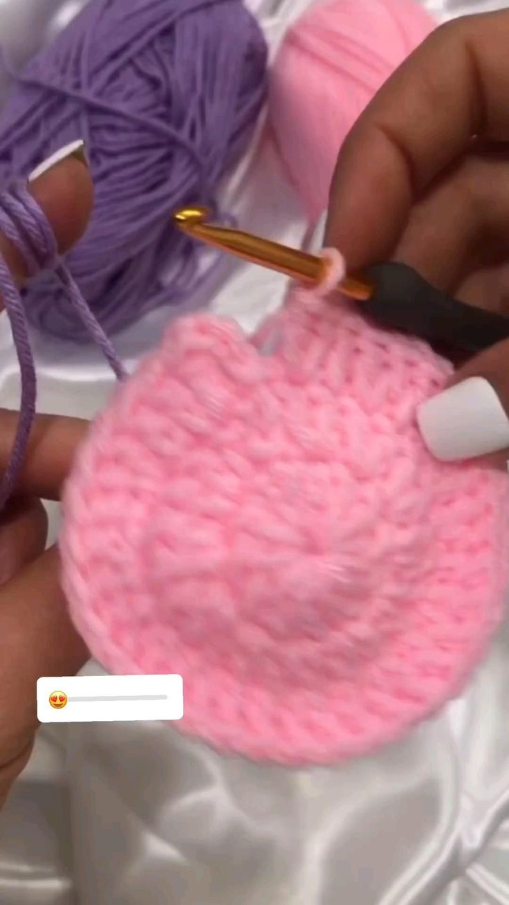 someone crocheting a pink ball of yarn