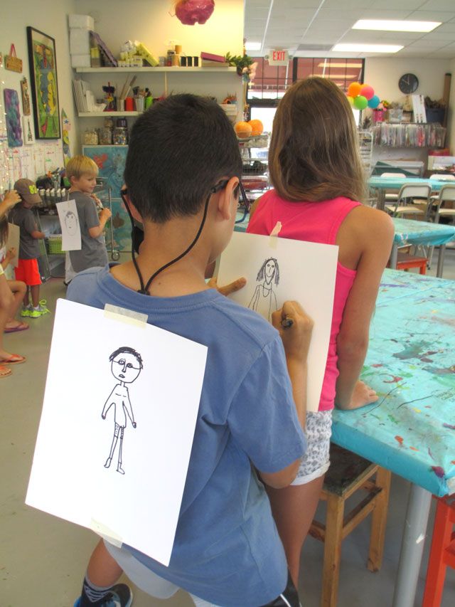 two children are holding drawings in front of them