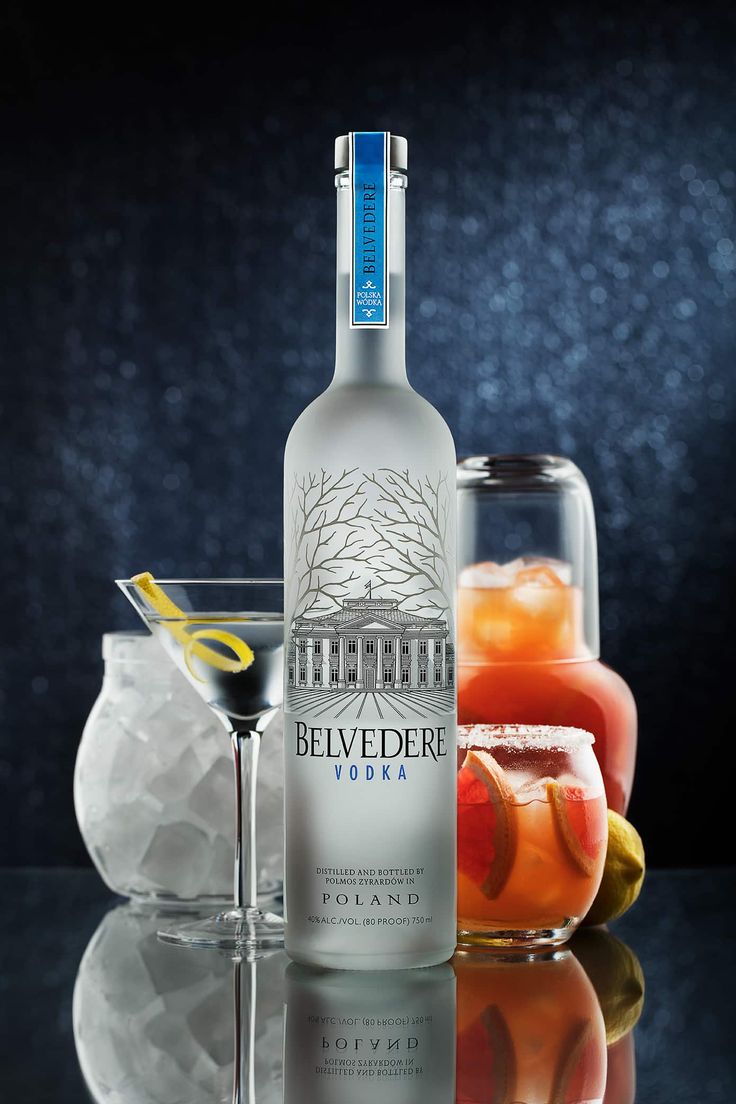 a bottle of belveder vodka next to two glasses filled with different types of drinks